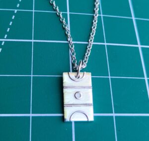 Silver netball court charm on green background