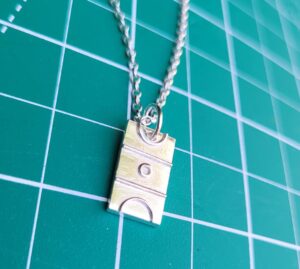 Silver netball court charm on green background