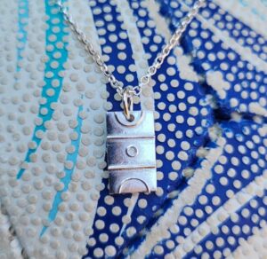 Silver netball court charm on green background