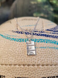 Silver netball court charm on green background