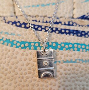 Silver netball court charm on green background