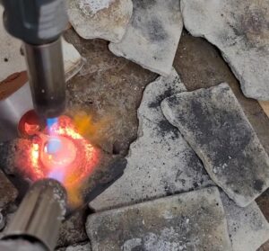 Silver being melted by torches and poured into a flask