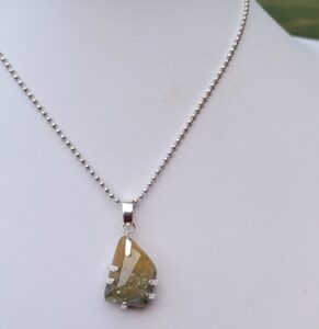 Rough sapphire in prong setting pendant.