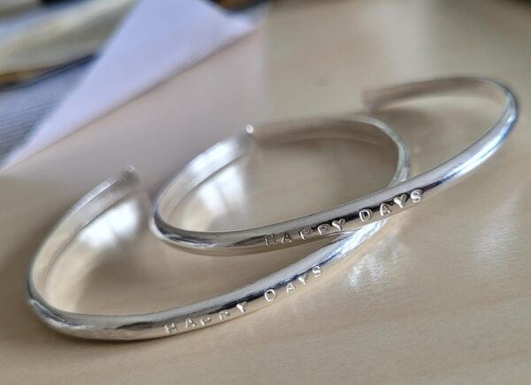 Silver cuff bangle with detail of a personalised message.