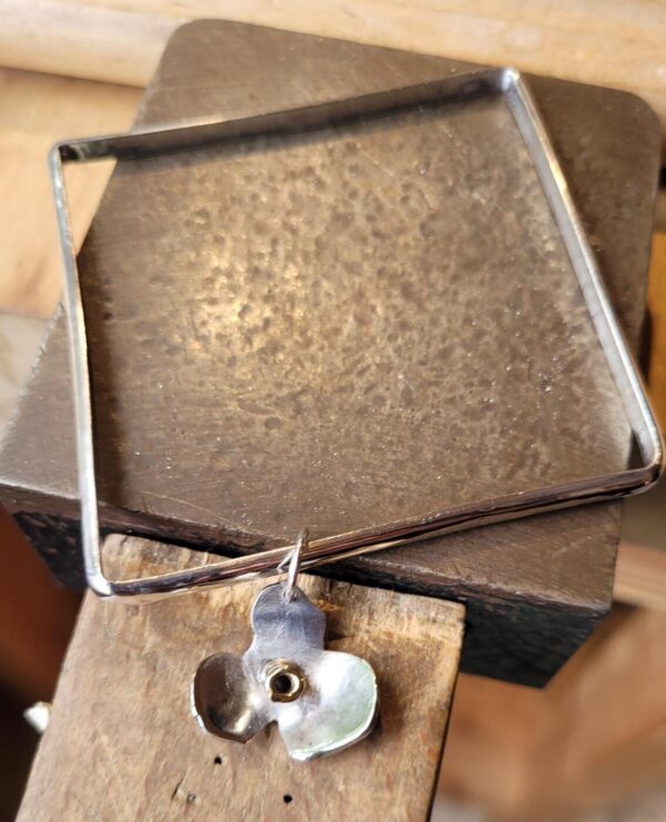 Silver square bangle with a flower charm.