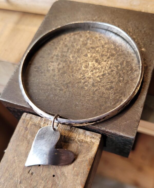 Silver bangle with heart charm.