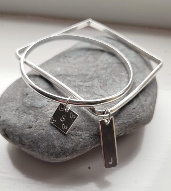 A square and round bangle with personalised charms attached.