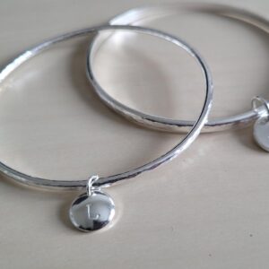 Silver bangles with personalised disc charms.