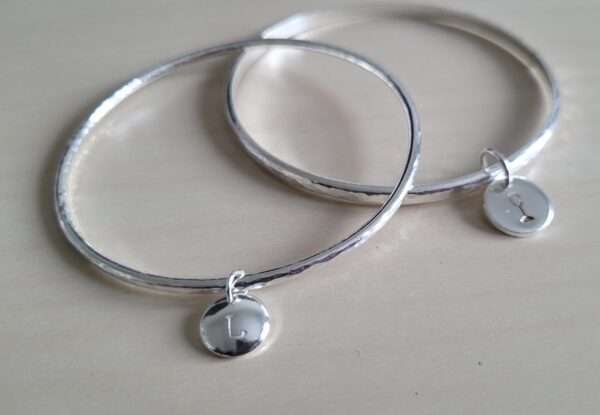 Silver bangles with personalised disc charms.
