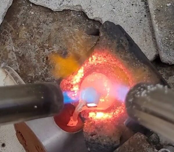 Pouring metal from a crucible into the flask.
